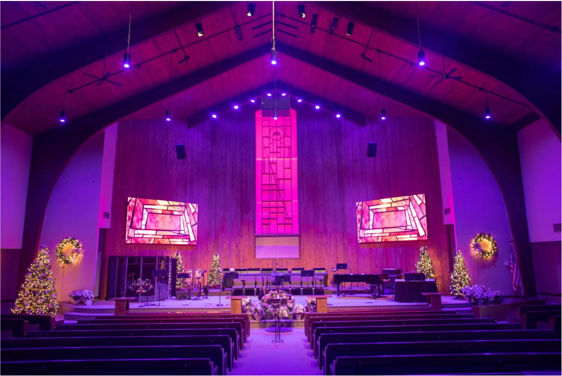 Two Absen video walls showcase images of stained glass windows on either side of the podium. 